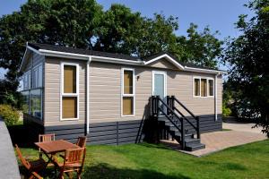 a tiny house with a staircase in the yard at Riverside Holiday Park in Amberley