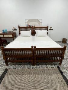 a bedroom with a large wooden bed with white sheets at Writer's Inn in Vaikom