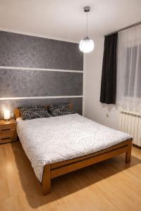 a bedroom with a bed with a gray wall at Apartman MARY in Belgrade