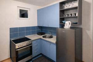 a blue kitchen with a sink and a refrigerator at Apartman MARY in Belgrade