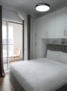 a bedroom with a large white bed and a chair at Shehu Apartments in Tirana