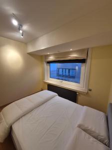 a bedroom with a white bed and a window at Faro in Blankenberge