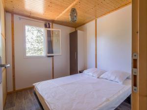 a bedroom with a white bed with a window at ZEcamping 3 étoiles avec terrain multisports mini golf 2km plage dog friendly in Cargèse