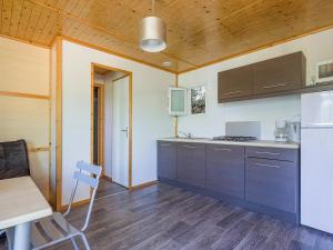 a kitchen with brown cabinets and a table and a stove at ZEcamping 3 étoiles avec terrain multisports mini golf 2km plage dog friendly in Cargèse