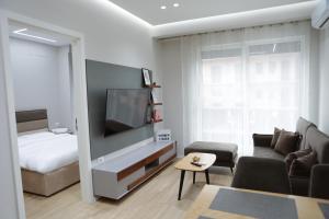 a living room with a couch and a tv and a bed at Shehu Apartments in Tirana