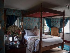 a bedroom with a four poster bed and blue walls at Ash Farm Country House in Little Bollington