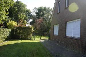 a house with a grass yard next to a building at Ferienhaus Alex in Großefehn 