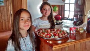 dos chicas de pie junto a un mostrador con una pizza en Cabañas De Madera, en La Unión