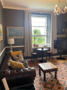 a living room with a leather couch and a table at Hidden Gem in Stirling