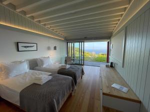 two beds in a room with a view of the ocean at Abrigos Baleeiros Turismo Rural in Feiteira
