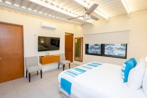 a bedroom with a white bed and a tv at Casa Itzae Hotel Boutique in Mérida