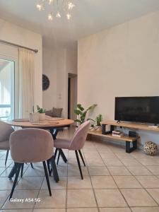 a living room with a table and chairs and a tv at Kerkis View House in Karlovasi