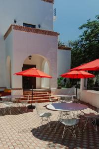 a patio with tables and chairs with red umbrellas at La Casona in Guadalajara