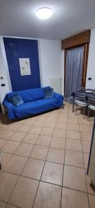 a blue couch in a room with a table and chairs at Chiara Apartment in Cervignano with 2 Double Beds in Cervignano del Friuli +1 photo