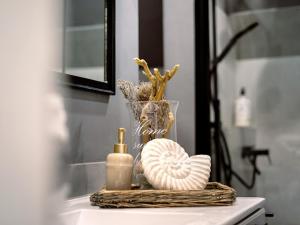 a bathroom sink with a bottle of soap and a shell at Ferienwohnung LA MAISON mit Sauna am See in Neuenkirchen +39 photos