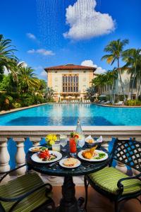 a table with plates of food next to a pool at Biltmore Hotel in Miami