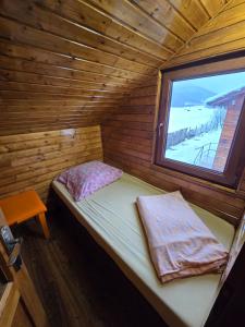 a small bed in a wooden room with a window at Cabana Soarelui - Valisoara in Vălişoara +71 photos