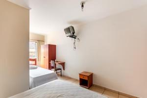 a bedroom with two beds and a tv on the wall at Agrishow 26 - Apartamento Single e Duplo in Ribeirão Preto