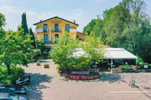 a yellow building with a lot of flowers and trees at Hotel Riel in Sirmione