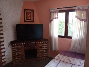 a living room with a television and a brick fireplace at La Carioca in Villa Gesell