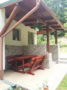 a wooden picnic table on a patio with a brick wall at Star Panzió in Harghita-Băi