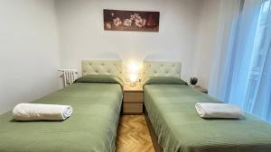 two beds in a room with green sheets and a table at Habitaciones en Don Ramon in Madrid