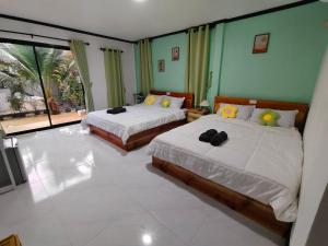a bedroom with two beds and a large window at Langkao Homestay Kohlibong หลังเขาโฮมสเตย์ เกาะลิบง in Ko Kwang