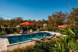 a pool with chairs and umbrellas in a yard at Holiday house Mia with pool in Imotski +35 photos