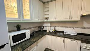 a kitchen with white cabinets and a microwave at Habitaciones en Don Ramon in Madrid +23 photos