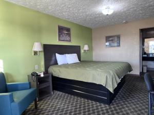 a bedroom with a bed and a blue chair at Deerfield inn & Suits in Smyrna