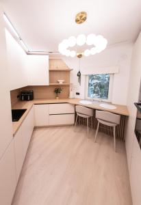 a kitchen with white cabinets and a table and chairs at Wabi Sabi Nest in Timişoara +28 photos
