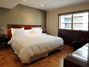 a bedroom with a large white bed with a window at Windsor Hotel in Córdoba
