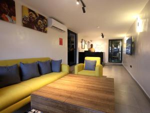 a living room with a yellow couch and blue pillows at Five Clover Hotel, Ilupeju in Lagos