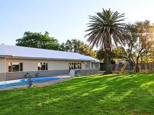 a house with a palm tree in front of a yard at The Bloemhof Stay in Bloemhof