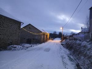 a snow covered street with a building and a christmas lights at Gite Happy Sun Flower in Virlet