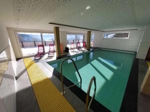 a large swimming pool with red chairs around it at Top 103 Lärchenhof in Mauterndorf