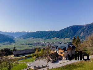 a large house on a hill with mountains in the background at Top 103 Lärchenhof in Mauterndorf