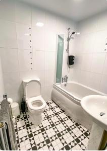 a bathroom with a toilet and a tub and a sink at Light & Spacious Loch Lomond Apartment in Alexandria +21 photos