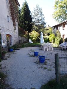 un cortile con sedie bianche e ombrellone e un edificio di L'AUBERGE CHEZ LEON a Le Chambon-sur-Lignon