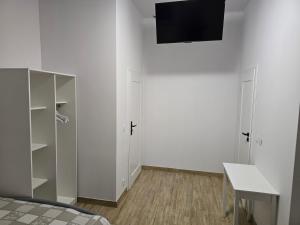 a white room with a bed and a tv on a wall at Rent0nline Brwinow Rooms in Brwinów