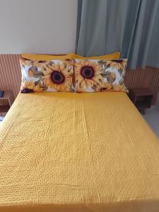 a yellow bed with two pillows on top of it at Suítes Concha do Sol in Maragogi +2 photos