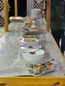 a long buffet with bowls of food on a table at Rum Lara Luxury Camp in Disah +70 photos
