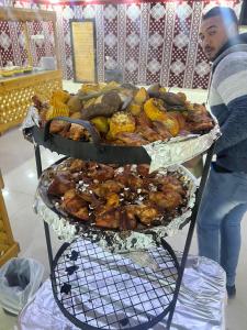 a man standing next to two trays of food at Rum Lara Luxury Camp in Disah