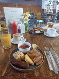 a wooden table with plates of breakfast foods and drinks at Lodge Dinorwig Hostel in Llanberis