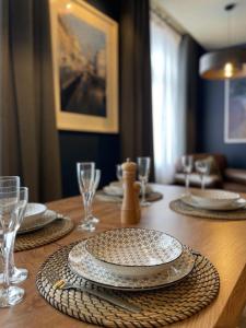 a wooden table with plates and glasses on top of it at Grand Appartement Hyper Centre in Lens