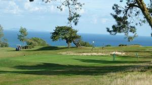 a golf course with the ocean in the background at Fernhill Hideaway in Charmouth