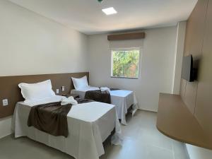 a room with two beds and a flat screen tv at Sun Route Hotel in Cabo de Santo Agostinho