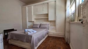 a bedroom with a bed with white cabinets and a window at Recanto da Serra Imperial in Lambari