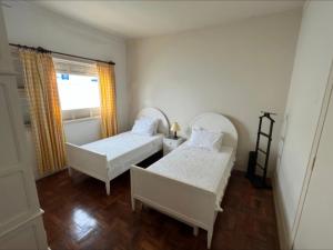 two beds in a small room with a window at Recanto da Serra Imperial in Lambari