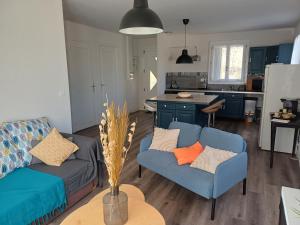 a living room with two blue couches and a kitchen at Gîte l'Ermitage in Cahors